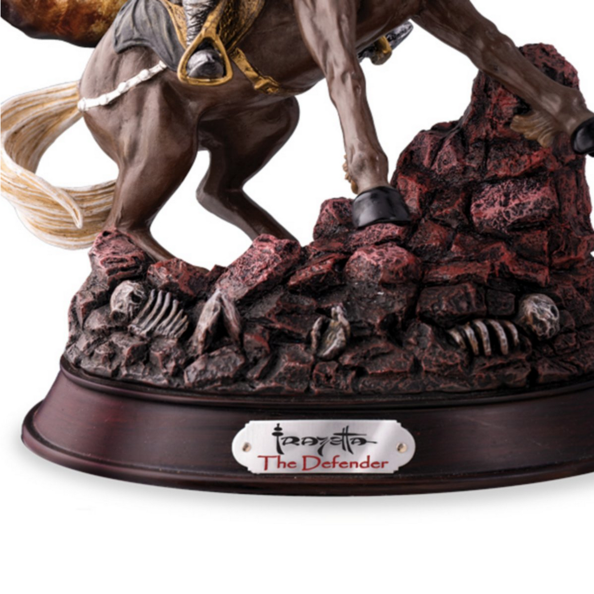 Close-up of the base of The Defender Sculpture, featuring rugged, bloodstained terrain strewn with skulls and skeletal remains. The sculpture’s wood-grain base includes a metal nameplate inscribed with "Frank Frazetta" and "The Defender."