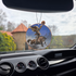 Frazetta Headless Horseman air freshener hanging in a car with black interior. The Frazetta Art Museum sits in the background with gloomy clouds overhead.