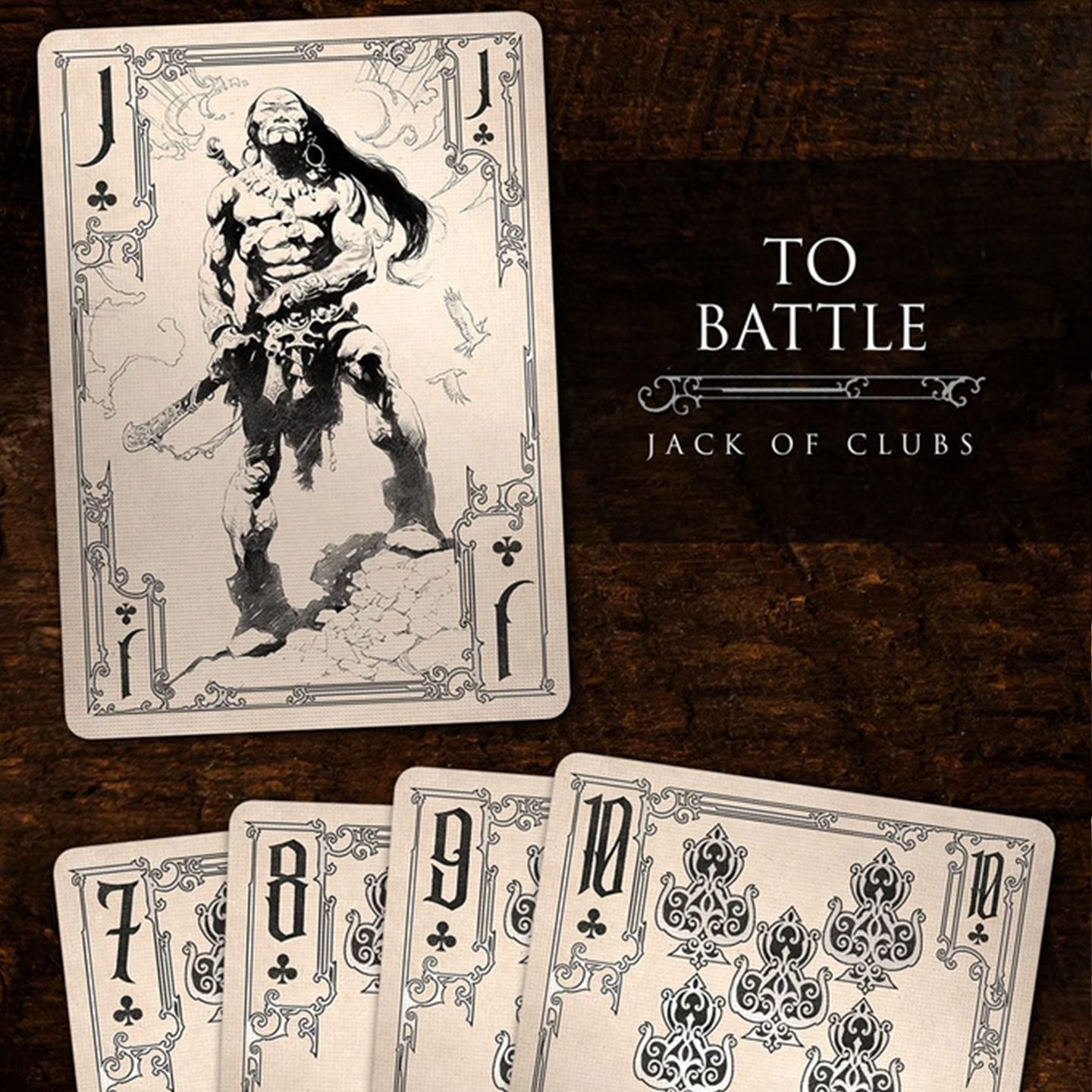 A close-up of a Jack of Clubs from the Frazetta Drawings Edition playing card deck. The card features an iconic Frazetta drawing with an ornate, vintage-style border with delicate filigree. Beneath it, additional cards are partially visible, showcasing intricate artwork and embossed detailing.