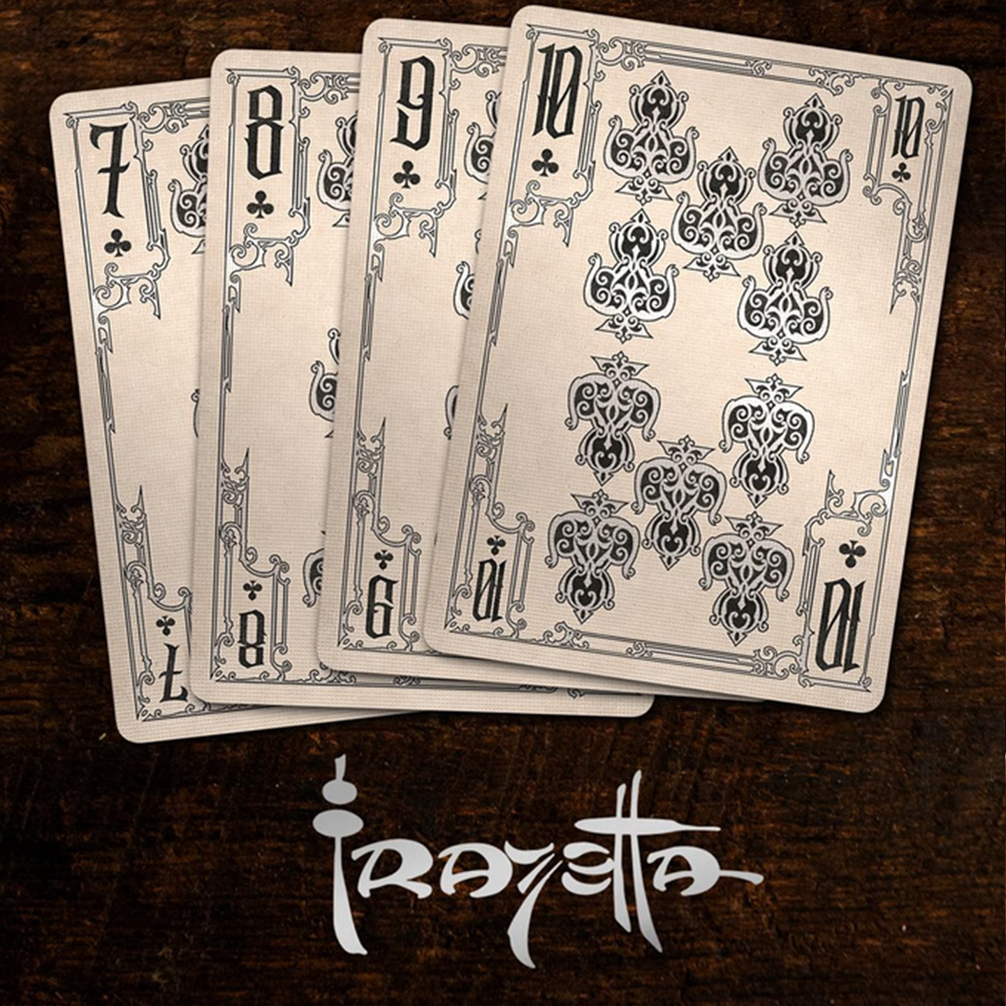 A close-up of cards seven through ten from the Frazetta Drawings Edition playing card deck. The cards feature an ornate, vintage-style border with delicate filigree and a stylized club symbol at its center. Beneath it, additional cards are partially visible, showcasing intricate artwork and embossed detailing.
