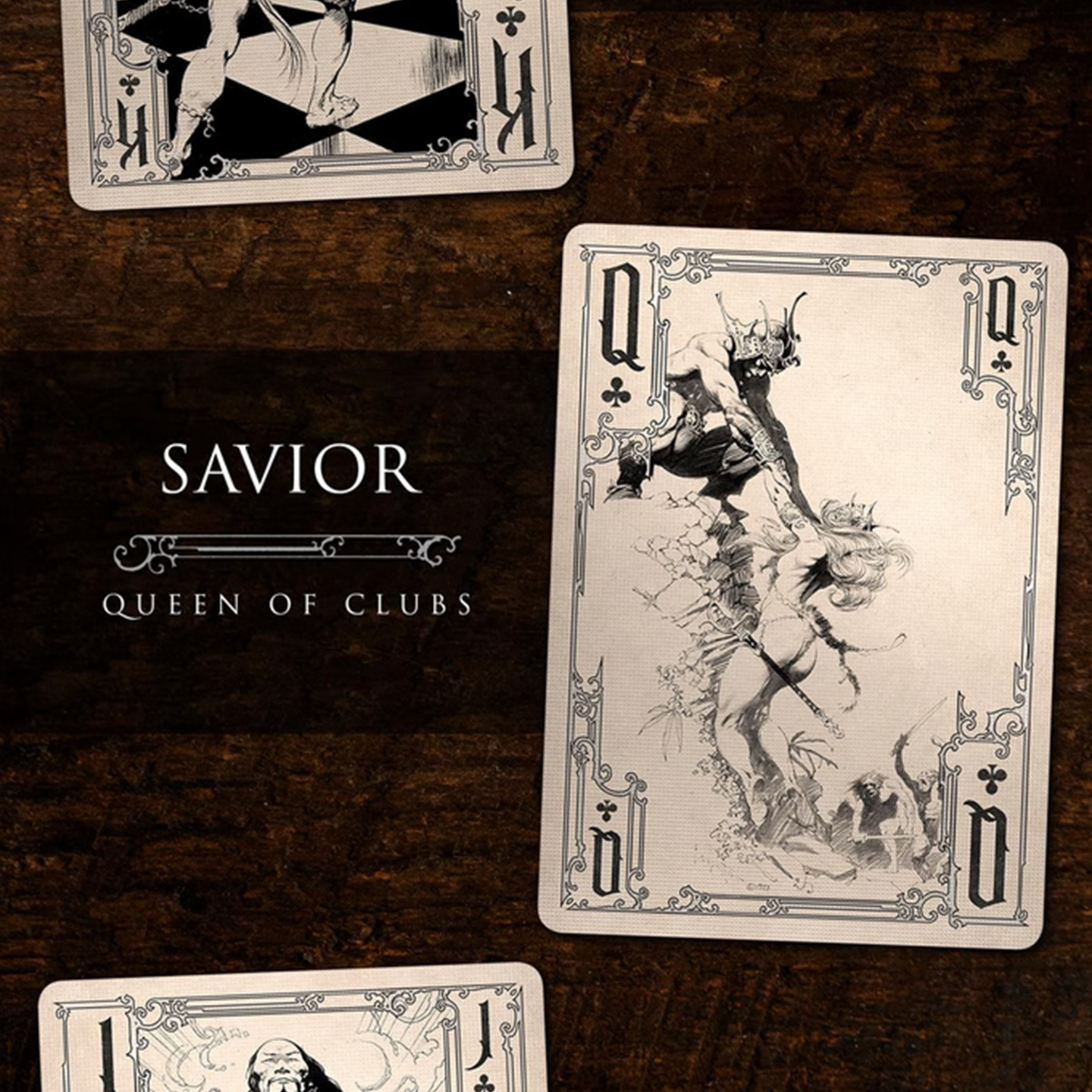 A close-up of a Queen of Clubs from the Frazetta Drawings Edition playing card deck. The card features an iconic Frazetta drawing with an ornate, vintage-style border with delicate filigree. Beneath it, additional cards are partially visible, showcasing intricate artwork and embossed detailing.