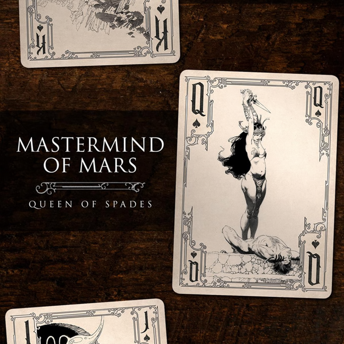 A close-up of a Queen of Spades from the Frazetta Drawings Edition playing card deck. The card features an iconic Frazetta drawing with an ornate, vintage-style border with delicate filigree. Beneath it, additional cards are partially visible, showcasing intricate artwork and embossed detailing.