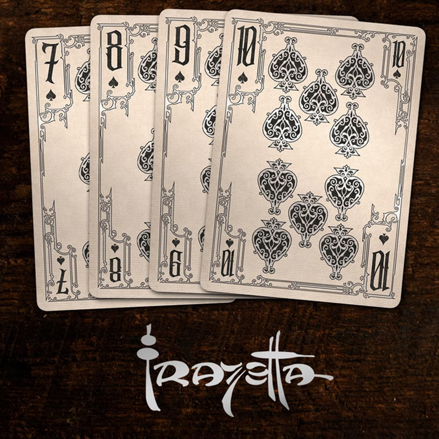 A close-up of cards seven through ten from the Frazetta Drawings Edition playing card deck. The cards feature an ornate, vintage-style border with delicate filigree and a stylized spade symbol at its center. Beneath it, additional cards are partially visible, showcasing intricate artwork and embossed detailing.