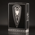 A high-end playing card deck from the Frazetta Drawings Edition is displayed against a sleek, dark background. The black tuck box features intricate embossing, silver foil accents, and a bold shield emblem with a stylized eagle at its center. The side of the box is adorned with the Frazetta signature, enhancing its luxury and collector’s appeal. The reflective silver details catch the light, emphasizing the deck’s premium craftsmanship.