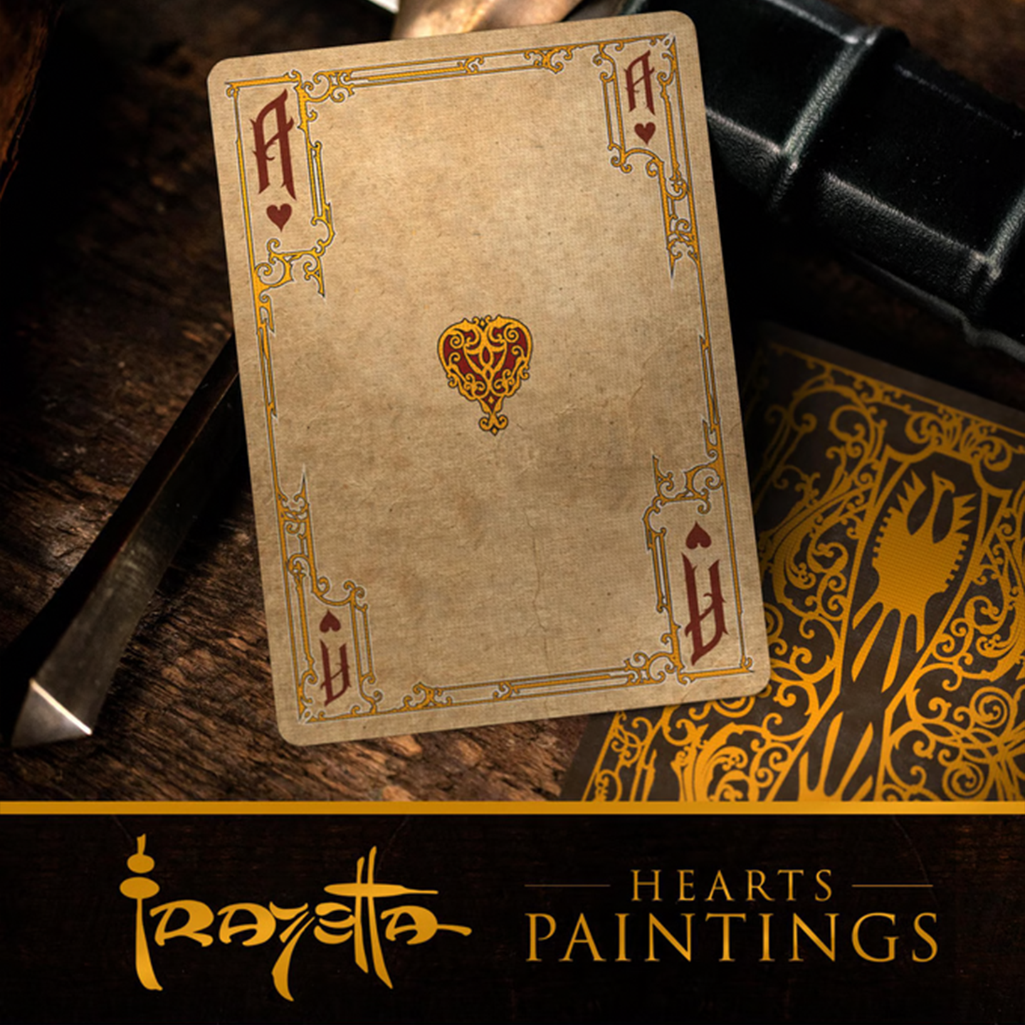 A close-up of an Ace of Hearts from the Frazetta Paintings Edition playing card deck. The card features an ornate, vintage-style border with delicate filigree and a stylized club symbol at its center. Beneath it, additional cards are partially visible, showcasing intricate artwork and embossed detailing. A knife rests nearby, enhancing the dramatic composition.