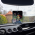 Photo of the Frazetta Swordsman of Mars air freshener hanging in a car with black interior. The Frazetta Art Museum sits in the background with gloomy clouds overhead.