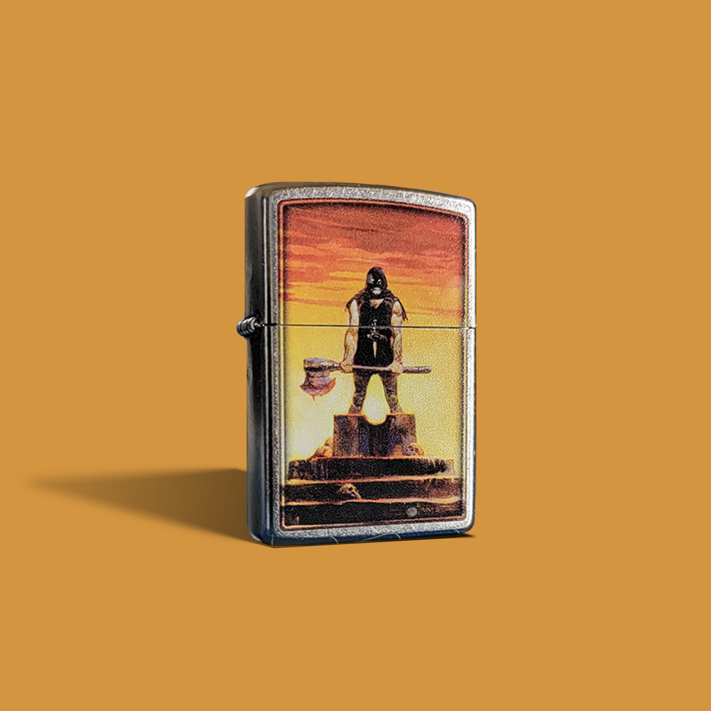 A Zippo lighter showcasing Frank Frazetta’s “Executioner” painting. A muscular, hooded figure stands atop a platform, gripping a massive axe, silhouetted against a blazing orange sky.