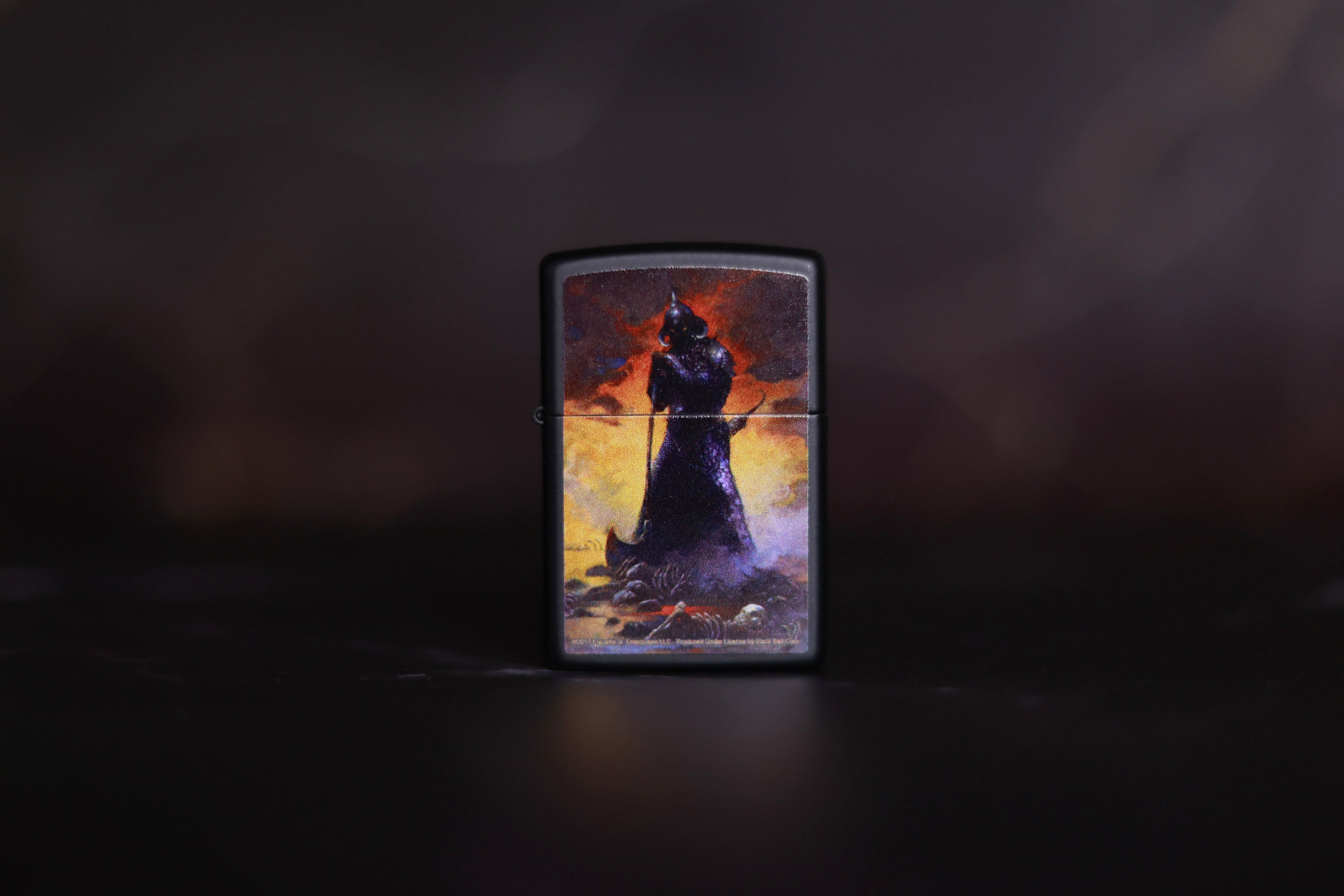 Black Zippo-style lighter featuring Frank Frazetta’s Death Dealer I artwork, showing a shadowy, armored warrior with glowing eyes standing amidst bones and smoke, illuminated by a fiery sky.