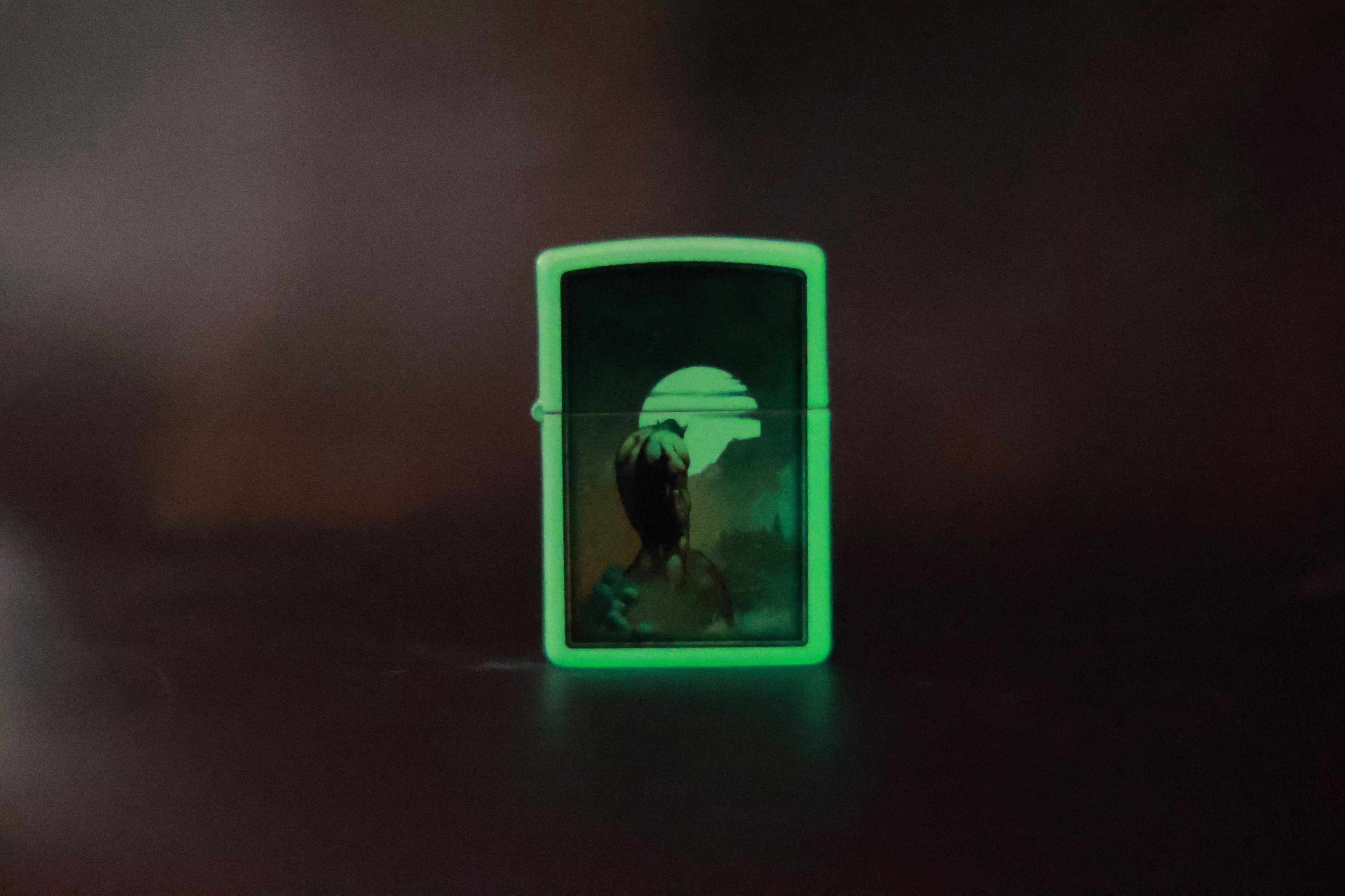 Glow-in-the-dark Zippo lighter featuring Frank Frazetta’s Night Stalker artwork, with a haunting figure silhouetted against a glowing moonlit sky.