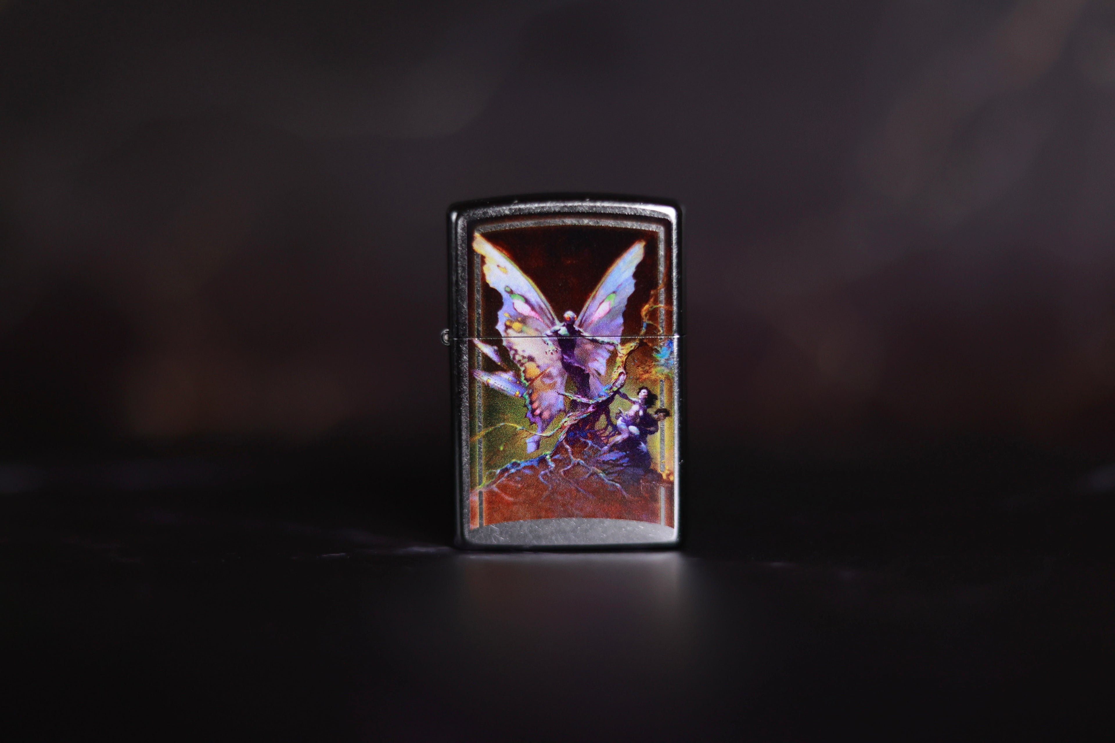 Zippo lighter featuring Frank Frazetta’s Mothman, depicting a striking winged figure with glowing eyes and eerie fantasy elements.