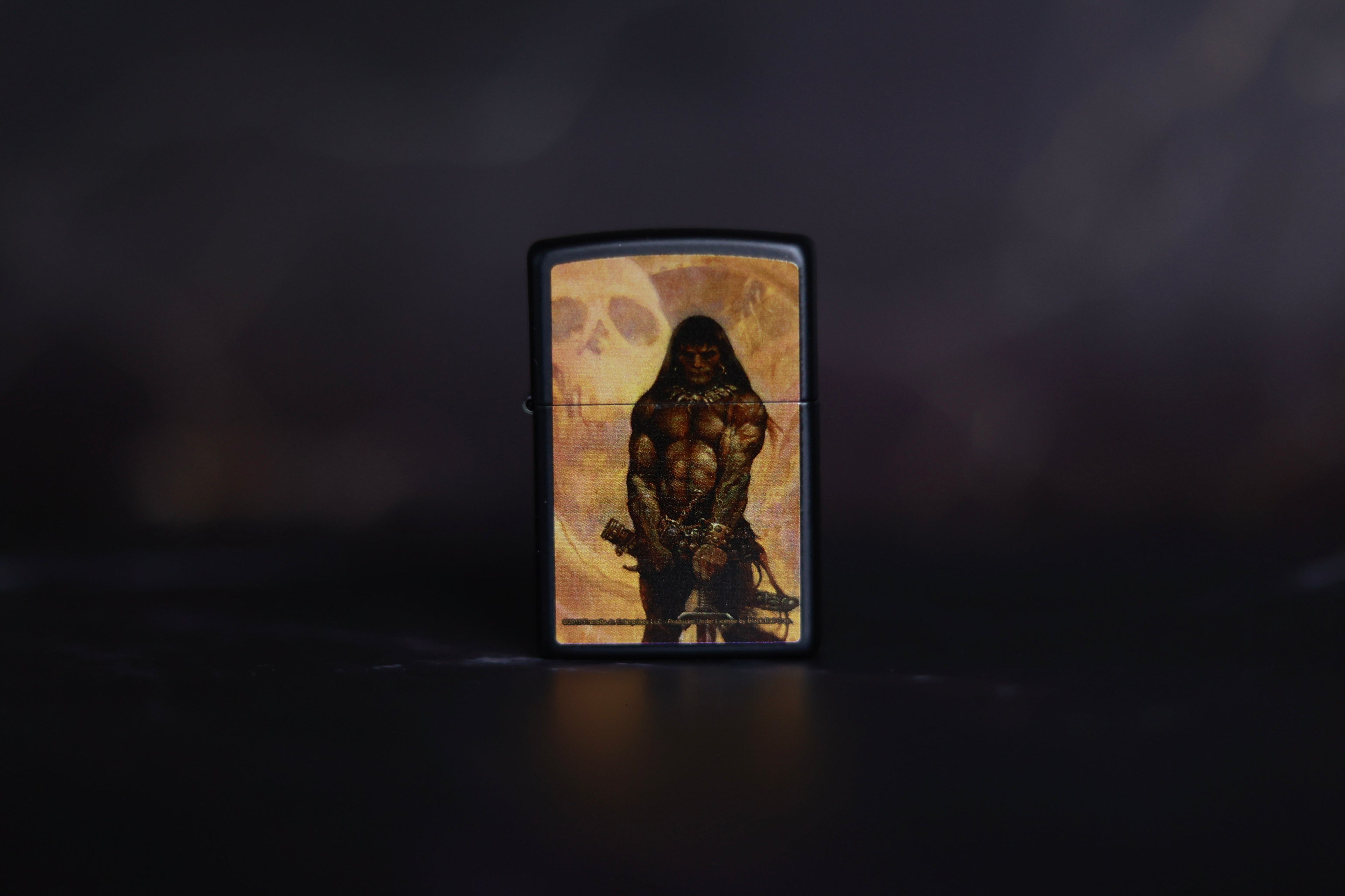Zippo lighter featuring Frank Frazetta’s The Barbarian, showcasing a powerful, muscular warrior standing before a looming skull backdrop.