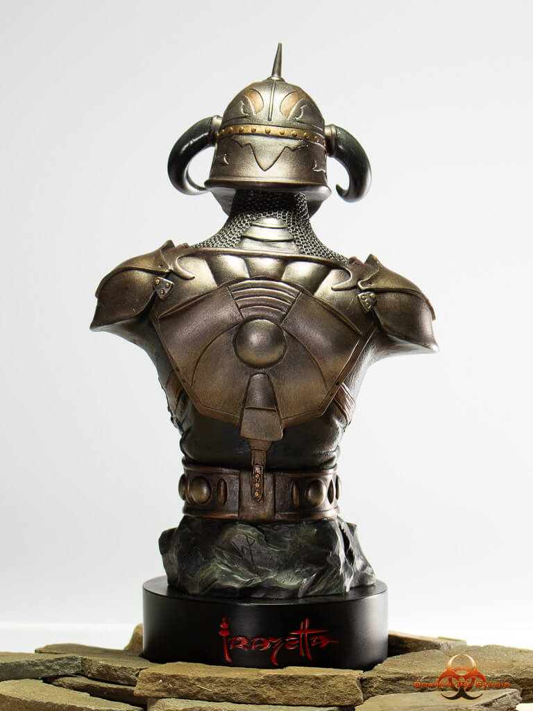A rear view of the 1/4 scale Death Dealer bust, showcasing the intricate detailing of the armored backplate, horned helmet, and chainmail. The statue is mounted on a black base featuring the Frazetta logo in red lettering, set on a stone-like surface.