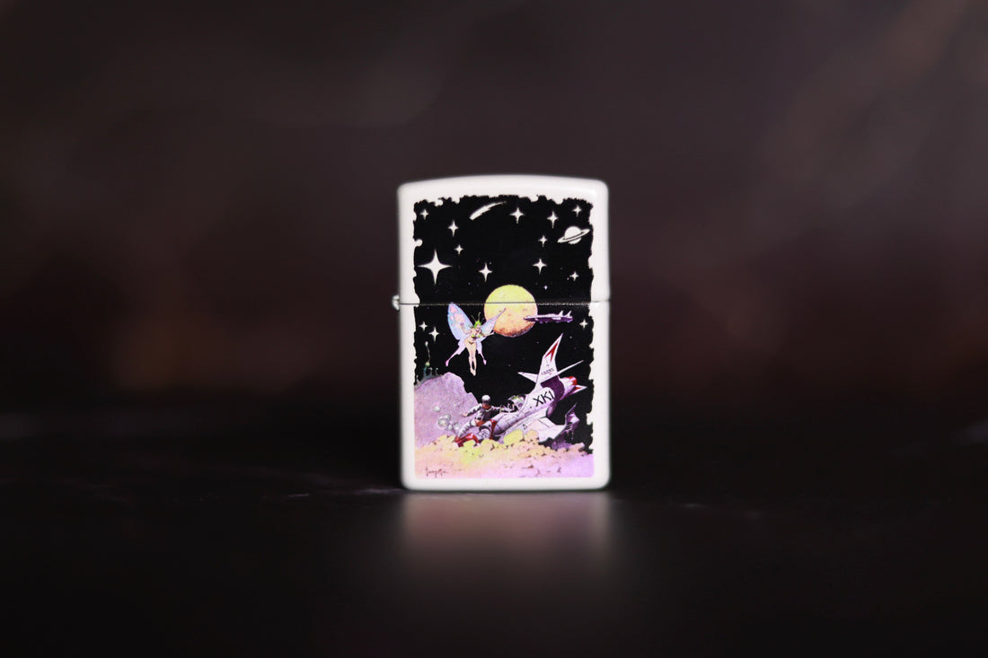 White Zippo-style lighter featuring Frank Frazetta’s whimsical sci-fi artwork, showing a fairy-like figure floating above a retro rocket ship and astronaut on an alien landscape, set against a star-filled cosmic background.