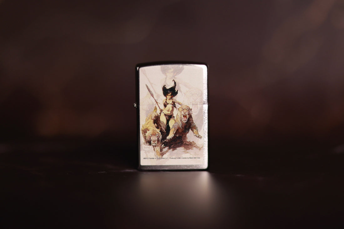 Zippo lighter featuring Frank Frazetta’s The Huntress artwork, depicting a fierce warrior woman standing between two saber-toothed cats against a pale backdrop.
